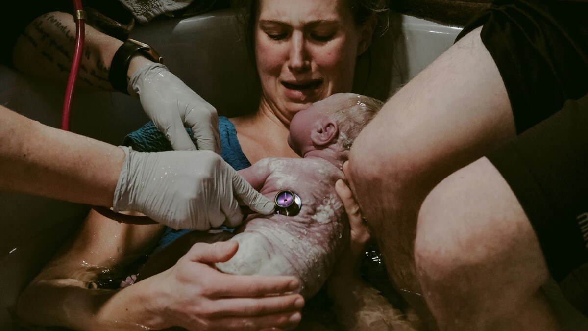woman holding baby in tub of water after birth